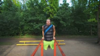 Park kaslı adam onun iş sırasında. Göğüs ve triceps dips, egzersiz.