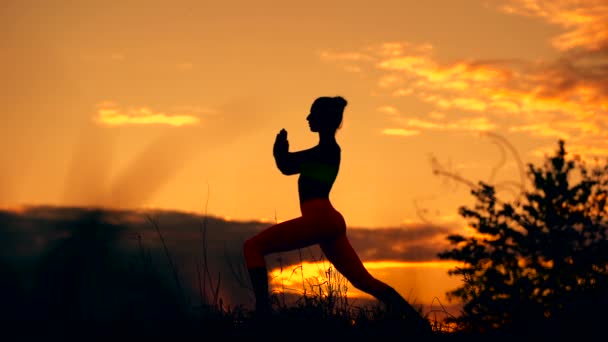 Силуэт профиля фитнес-женщины, растягивающейся на восходе солнца на заднем плане — стоковое видео