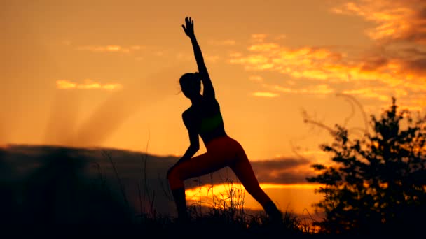 Silhouette of a fitness woman profile stretching at sunrise with the sun in the background — Stock Video