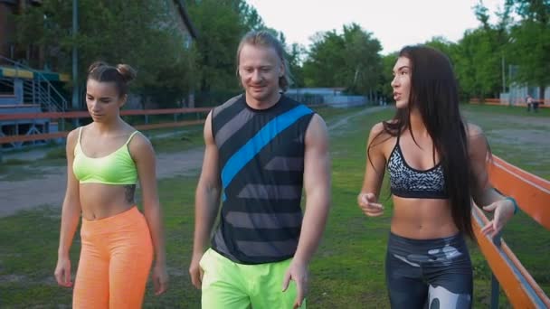 Sports people. The boy and two girls are after your workout fun and something to discuss — Stock Video