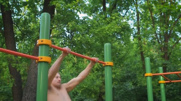 Estilo de vida deportivo, entrenamiento callejero. Hombre muscular realiza un ejercicio de toma de corriente. Campo de deportes al aire libre . — Vídeos de Stock