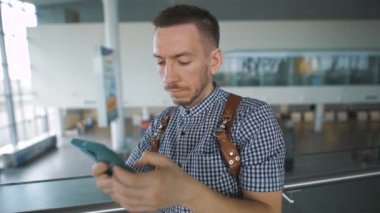 Elinde bir akıllı telefon ile havaalanında şık hipster.