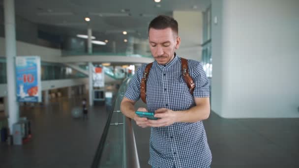 Elegante hipster en el aeropuerto con un smartphone en la mano . — Vídeo de stock