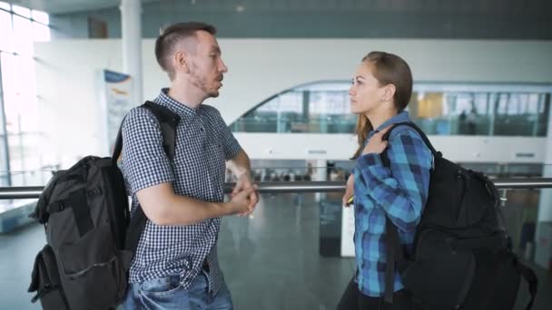 Um par de jovens no aeroporto. Anunciado pouso a bordo da aeronave, os passageiros vão para o portão . — Vídeo de Stock