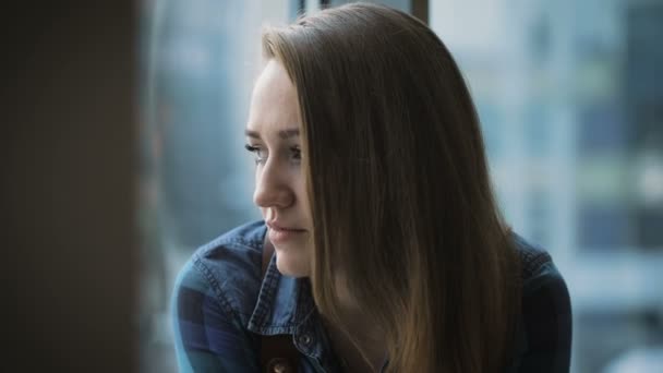 Portrait de jolie fille aux cheveux longs. Étudiant assis près de la fenêtre et des conversations amicales avec quelqu'un . — Video