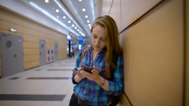 Hon reser med ryggsäck. Det är på flygplatsen väntar på flyget. — Stockvideo