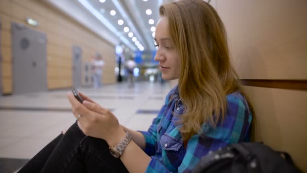 Viajero de pie mujer usando un teléfono inteligente y esperando en un aeropuerto — Vídeos de Stock