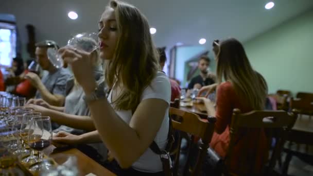 Groep jongeren op een wijnproeverij. Meisje met een glas wijn, het smaakt het drankje smaak en geur. — Stockvideo