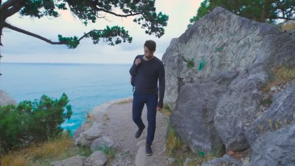 Young man goes with a backpack on his back through the beautiful countryside. — Stock video