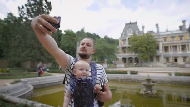 Otec držel svého mladého syna a dělá selfie telefon. Cestují spolu — Stock video