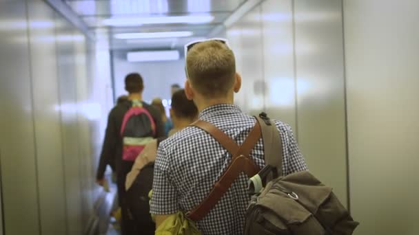 Den unge mannen går ner i korridoren till ombord på flygplanet. — Stockvideo