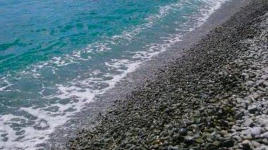 Çakıl plajı ve deniz. Kıyıda haddelenmiş dalgalar