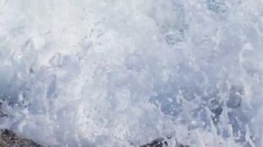Dalgalar kıyıya taş, kırık ve tıslayan haddelenmiş.