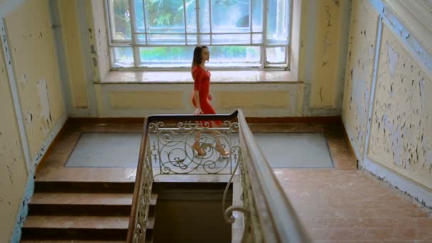 Beautiful girl in a red dress goes up the stairs. — Stock Video