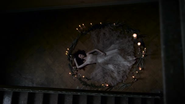 Ritual sacrifice or challenge spirits. Slim girl lying in a circle of candles and branches, she is a virgin. — Stock Video