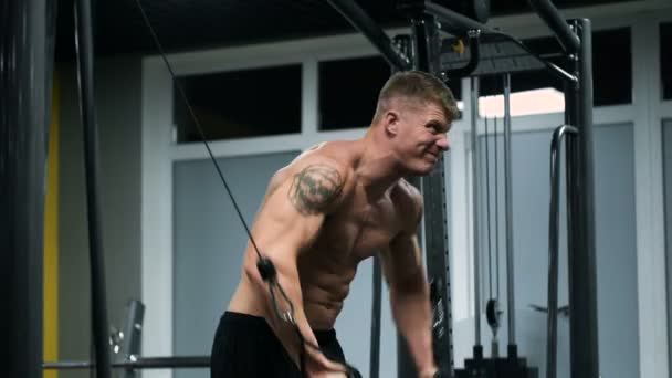 Atleta muscular en el gimnasio, haciendo ejercicio pesado . — Vídeo de stock