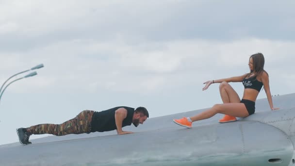 Guy and girl in army style clothing climbed on the old plane. — Stock Video