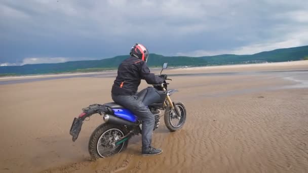 Extrémní motocyklista jede na písčité břehu řeky. — Stock video