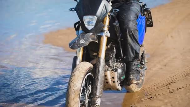 Joven motociclista en la orilla del río, se prepara para comenzar — Vídeo de stock