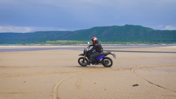Η αίσθηση της ελευθερίας και της αισθητικής Moto. Μοτοσικλετιστής ιππασία με το ποδήλατό του σε αμμώδη παραλία. — Αρχείο Βίντεο