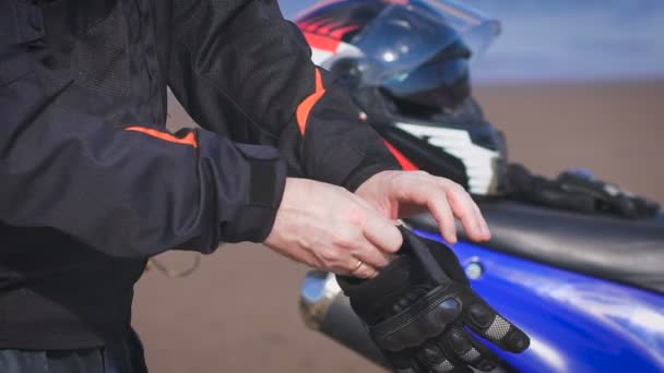 Motociclista in strada accanto alla sua moto, indossa guanti . — Video Stock