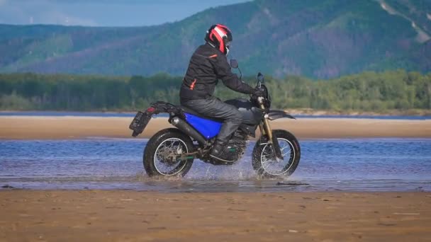 Conducción extrema de una motocicleta. Un ciclista experto en el borde del agua — Vídeo de stock