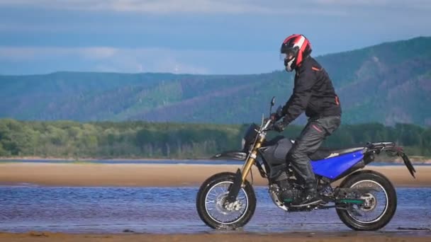 The feeling of freedom and Moto aesthetics. Motorcyclist riding on his bike on sandy beach. — Stock Video