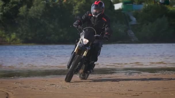 Das Gefühl von Freiheit und Moto-Ästhetik. Motorradfahrer auf seinem Fahrrad am Sandstrand. — Stockvideo