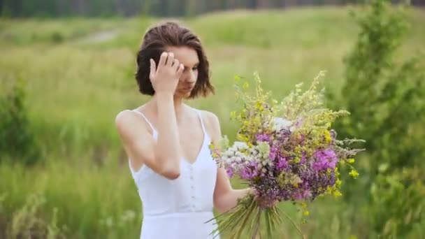 Summer flowering field and a beautiful girl in a white sundress. — Stock Video