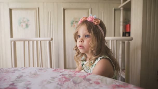 Buscando inspiración. Niña pensativa mirando hacia otro lado mientras está sentada a la mesa en una habitación luminosa . — Vídeos de Stock