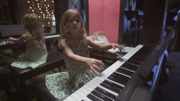 Красива маленька дівчинка грає на піаніно в кімнаті — стокове відео