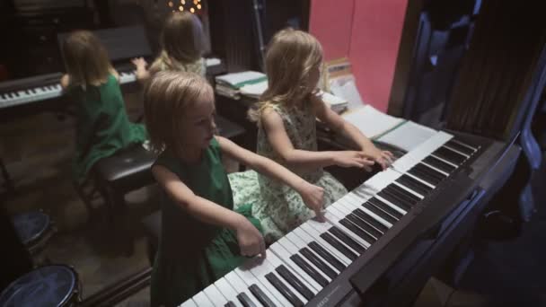 Due belle bambine stanno suonando il pianoforte in una stanza — Video Stock