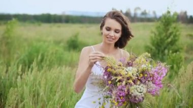 Kır çiçekleri elinde bir buket mutlu genç kız.