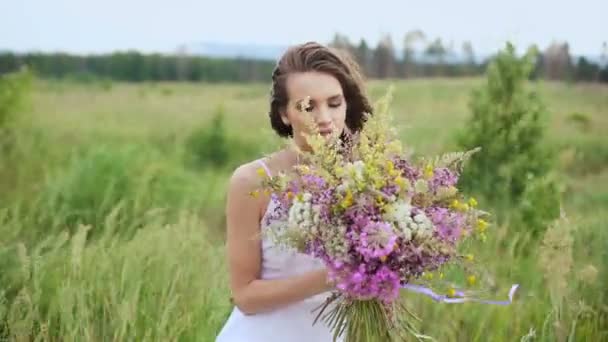 Glad ung flicka med en bukett av vilda blommor i sin Hand. — Stockvideo