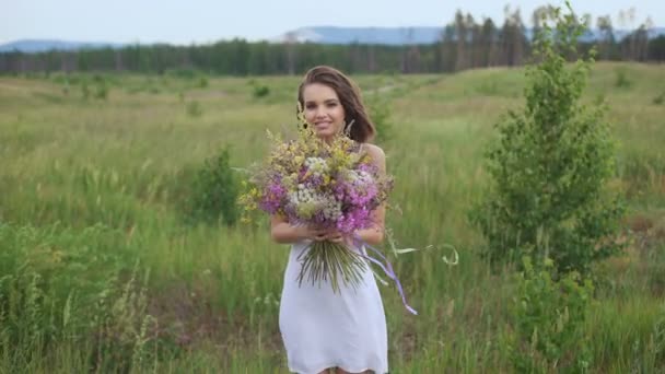 Bela mulher inspirada mantém um buquê de flores silvestres . — Vídeo de Stock