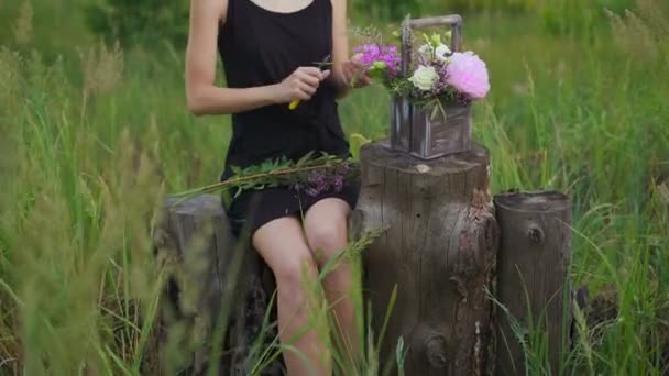 Slim ragazza in abito nero opere di fiori al tramonto — Video Stock