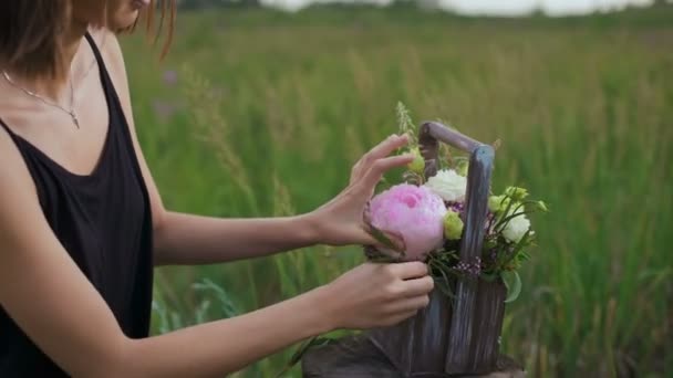 Schlankes Mädchen im schwarzen Kleid arbeitet mit Blumen bei Sonnenuntergang — Stockvideo