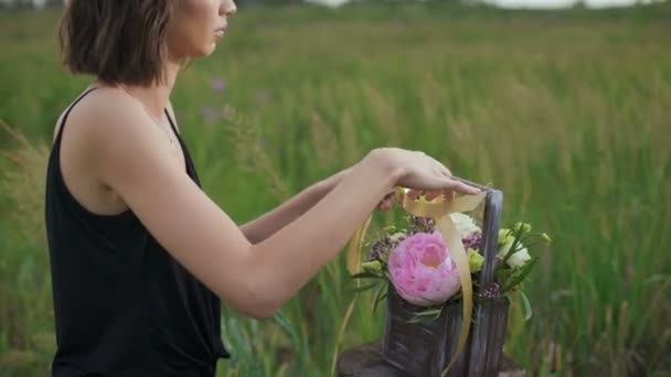 Szczupła dziewczyna w czarnej sukni działa kwiatów o zachodzie słońca — Wideo stockowe