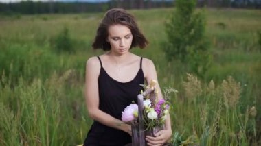 Taze çiçekler şık bir çekmecede. Akşam çiçekli bir alanda güzel esmer.