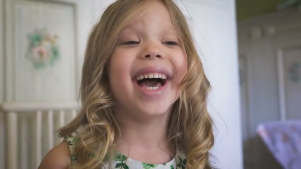 Ένα όμορφο μικρό κορίτσι χαμογελά στο φωτεινό δωμάτιο — Αρχείο Βίντεο