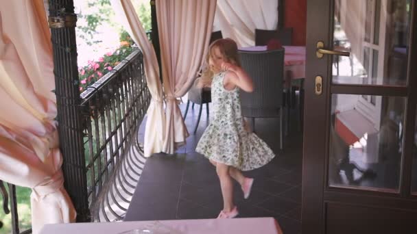 Seorang gadis pirang kecil yang bahagia melompat di balkon . — Stok Video