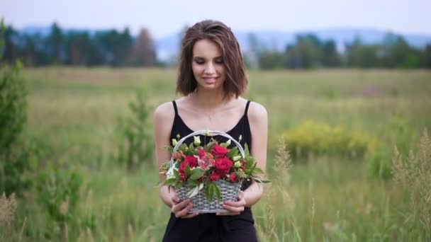 Retrato de una hermosa niña con una cesta de flores en sus manos . — Vídeo de stock