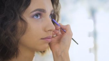Profesyonel makyaj sanatçısı bir photoshoot için güzel bir genç yüz makyaj uygulayarak