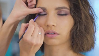 Profesyonel makyaj sanatçısı bir photoshoot için güzel bir genç yüz makyaj uygulayarak