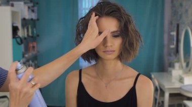 Bir stilist güzel bir gelin için makyaj ve saç modeli yapıyor