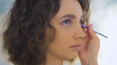 Profesyonel makyaj sanatçısı bir photoshoot için güzel bir genç yüz makyaj uygulayarak