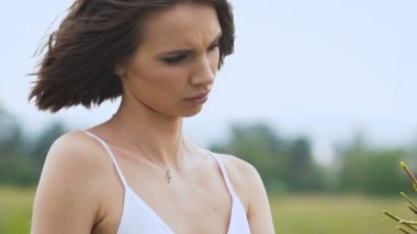 Yeşil alanda duran bir çiçek demeti yapan genç bir kadın