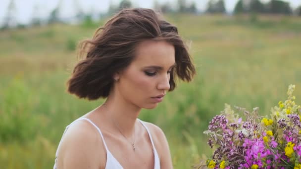 Eine junge Frau auf der grünen Wiese mit Blumenstrauß — Stockvideo