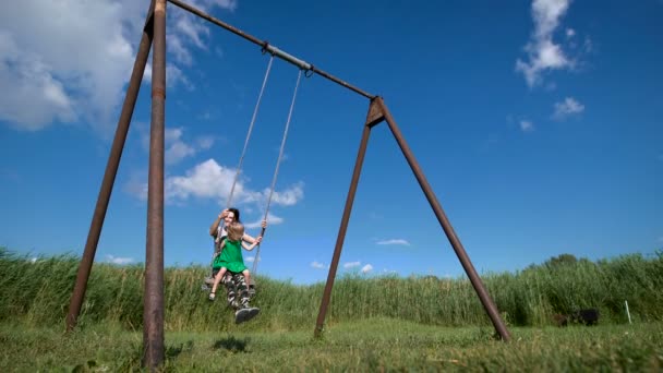 Urocza dziewczynka z jej piękną matką bawią się na zewnątrz huśtawka — Wideo stockowe