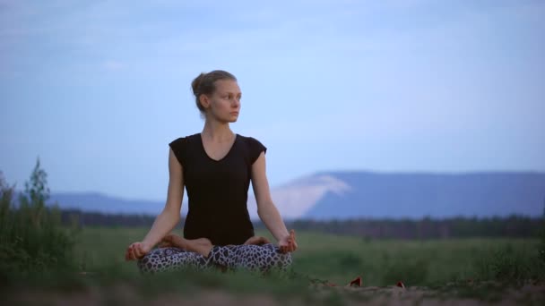 Een mooie jonge dame in een lotus houding zitten — Stockvideo